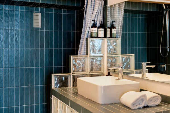 A bathroom with a large mirror, two sinks, a shower, and a towel rack.