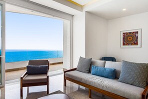 A modern living room with a sofa and armchair, a large window with a view of the ocean, and a framed artwork on the wall. - Blue Horizon 502 | 1BR/2BA Puerto Vallarta Ocean View, Pool & Gym (Puerto Vallarta)