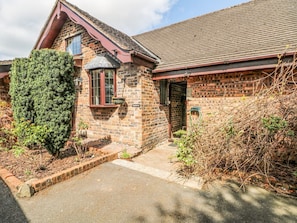 A brick house with a sloped roof, a window, and a door.
