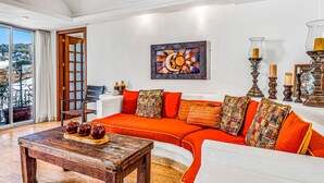 Een moderne woonkamer met een gebogen oranjesofa, een houten salontafel en een groot raam met uitzicht op de stad.