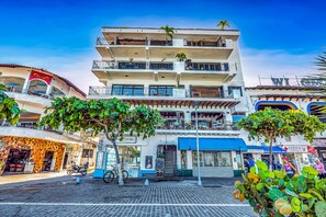 A multi-story building with balconies, a pharmacy, and a restaurant. - Downtown Malecon beach front, AC, walk to restaurant/bars, rooftop 360 views (Puerto Vallarta)