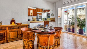 Een eetruimte met een ronde tafel, houten stoelen en een keuken op de achtergrond.