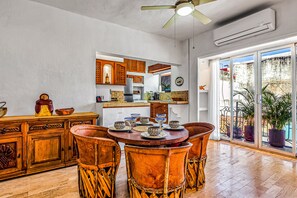 A dining area with a round table, wooden chairs, and a kitchen in the background. - Downtown Malecon beach front, AC, walk to restaurant/bars, rooftop 360 views (Puerto Vallarta)