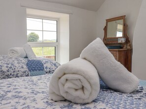 Ein Schlafzimmer mit Bett, Fenster, Spiegel und einem Holzschrank.