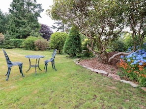 Een tuin met een tafel en stoelen, omringd door verschillende planten en bomen.