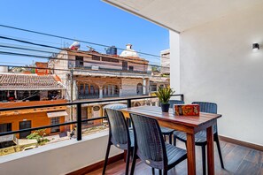 A balcony with a wooden table and chairs, a potted plant, and a game box. - 2BR Serenity Condos #201 in PV near ocean, pool, BBQ (Puerto Vallarta)