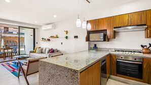 Eine moderne Küche mit Granit-Arbeitsplatten, Holzschränken, einem eingebauten Backofen und einer Mikrowelle.