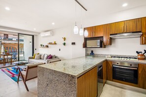 A modern kitchen with granite countertops, wooden cabinets, a built-in oven, and a microwave. - 2BR Serenity Condos #201 in PV near ocean, pool, BBQ (Puerto Vallarta)