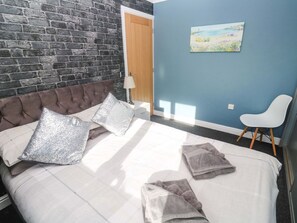 A bedroom with a bed, pillows, a chair, a painting, and a door. - Cherry Tree House, Penzance (Penzance)