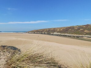 Ein Strand mit Dünen, einem klaren Himmel und ruhiger See.