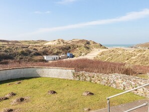 Eine Küstenlandschaft mit einer Steinmauer, einer Rasenfläche und einem kleinen Gebäude mit blauem Dach.