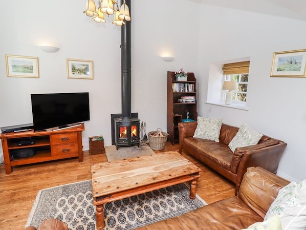 Ein Wohnzimmer mit Fernseher, Kamin, Sofa und Bücherregal.