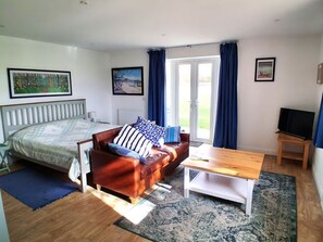 A bedroom with a bed, a sofa, a TV, and a window with curtains. - Buttercups at Midway, Kington (Worcester)