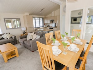 A modern living room with a dining area, a kitchen in the background, and a large window. - The Last Resort, Pendine (United Kingdom)