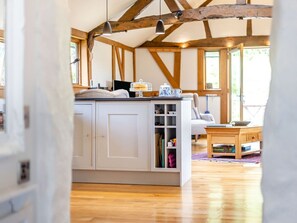 Cocina con armarios blancos, una isla de madera y vistas a una sala de estar con sofá y una mesa de centro.