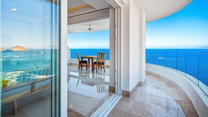 Ein Balkon mit Meerblick, Deckenventilator und Tisch mit Stühlen.
