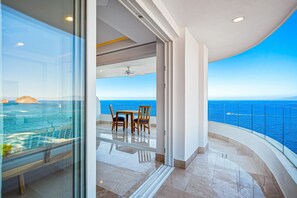 A balcony with a view of the sea, a ceiling fan, and a table with chairs. - Blue Horizon 701 | 1BR/2BA in Puerto Vallarta, Ocean View, Pool & Gym (Puerto Vallarta)