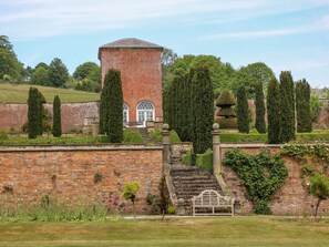 A brick tower with arched windows, a stone staircase, and neatly trimmed hedges. - The Card House, Hopton (Matlock)