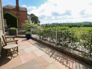 A patio with a view of a brick building, a metal fence, and a garden. - The Card House, Hopton (Matlock)