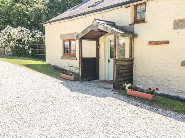 A building with a gravel driveway, a wooden door, and a sign that reads 'THE FARM HOUSE.'