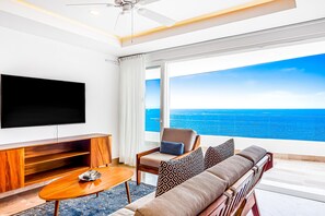 A modern living room with a large TV, a sofa, a chair, and a view of the ocean. - Ocean-view Puerto Vallarta condo with pool, gym (Puerto Vallarta)
