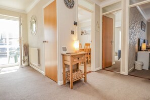 A room with a wooden desk, a chair, a lamp, a clock, and a door leading to another room. - Echo Beach, Seasalter (Whitstable)