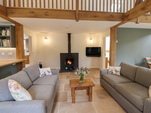 Una sala de estar con chimenea, sofás, televisor y una mesa de centro de madera.