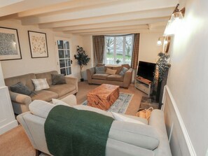 A living room with a sofa, a coffee table, a TV, and a window with curtains.