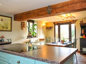 A kitchen with a large island, wooden beams, a dining area with chairs, and a window with a view. - Lazy Hare at Jen's Orchard, St Giles On The Heath (Launceston)
