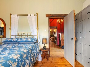 A bedroom with a four-poster bed, a bedside table with a lamp, and a wardrobe. - Lazy Hare at Jen's Orchard, St Giles On The Heath (Launceston)