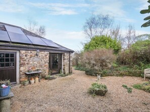 A stone building with a gravel driveway, solar panels, and a garden with potted plants. - Lazy Hare at Jen's Orchard, St Giles On The Heath (Launceston)