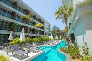 A hotel with a pool, lounge chairs, and palm trees. - Unit 2303 Beachfront Pool-facing + Sea View (Choeng Thale)