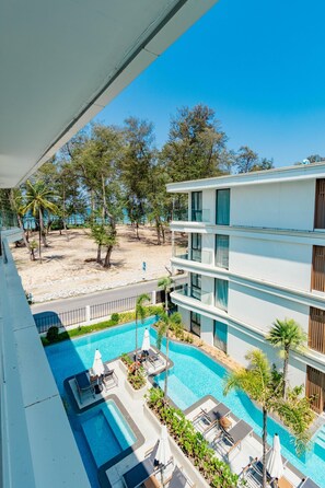 A multi-story hotel with a pool area, outdoor seating, and a view of the beach. - Unit 2303 Beachfront Pool-facing + Sea View (Choeng Thale)