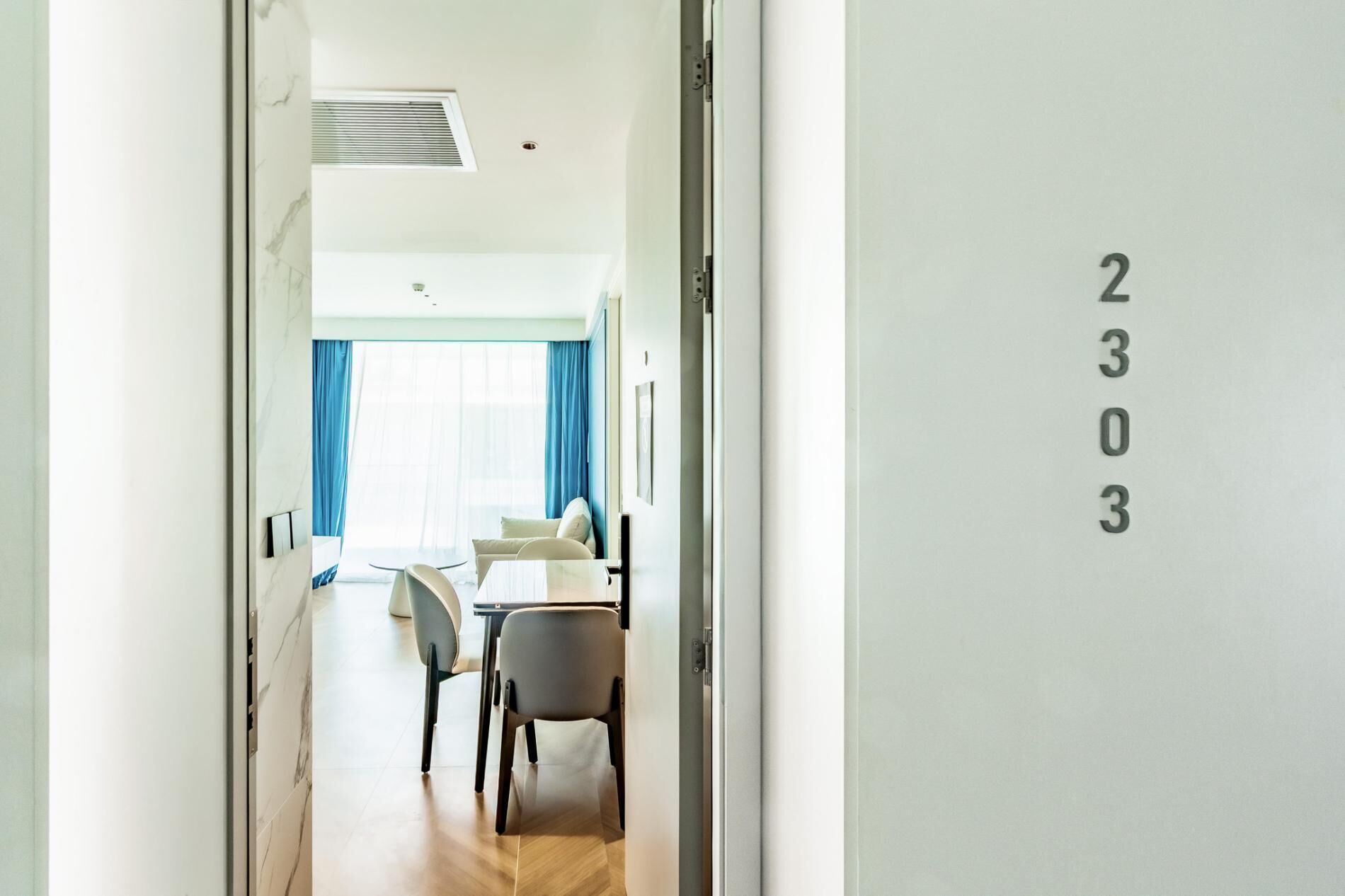 A hotel room with a dining area, a bed, and a bathroom.