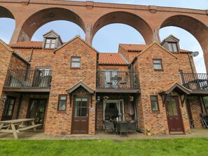 A brick building with three arches, a balcony, and a patio area with furniture. - Maplebeck, Whitby, North Yorkshire (Whitby)
