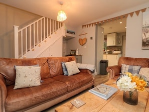 A living room with a brown leather sofa, a wooden coffee table, and a staircase. - Maplebeck, Whitby, North Yorkshire (Whitby)