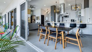 A modern kitchen with a dining area, featuring a large island, bar stools, and a ceiling fan. - Dog-friendly ocean view penthouse & studio with a full kitchen & kitchenette (Puerto Vallarta)