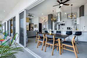 Eine moderne Küche mit Essbereich, inklusive einer großen Kochinsel, Barhocker und Deckenventilator.
