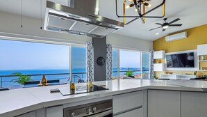 A modern kitchen with a large island, built-in oven, and a view of the ocean. - Dog-friendly ocean view penthouse & studio with a full kitchen & kitchenette (Puerto Vallarta)