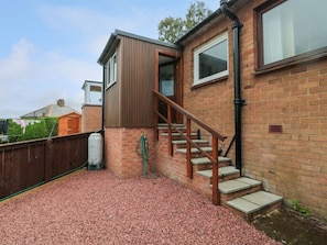 A residential property with a brick exterior, a wooden staircase, and a water tank. - Crosby Cottage, Wooler, 3 bed. (Wooler)
