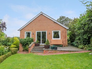 A single-story brick house with a front porch, a bench, and a small garden area. - Crosby Cottage, Wooler, 3 bed. (Wooler)