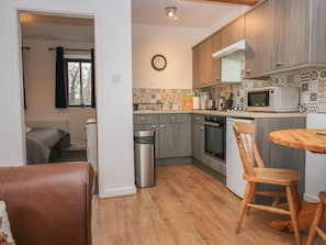 A compact kitchen with wooden cabinets, a microwave, a kettle, and a trash bin. - Little Winder, Askham, Cumbria (Penrith)