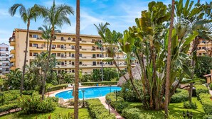 Un hôtel doté d’une piscine, entourée d’une végétation luxuriante et de palmiers.