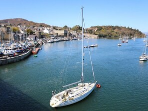 A harbor with boats, a sailboat in the foreground, and a town in the background. - Bryn Tawel in Penmachno, Conwy (Betws-y-Coed)