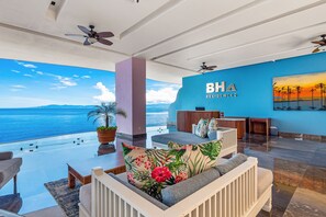 Ein geräumiger Wohnbereich mit Meerblick, eine blaue Wand mit dem Logo "BH Residences" und Deckenventilatoren.