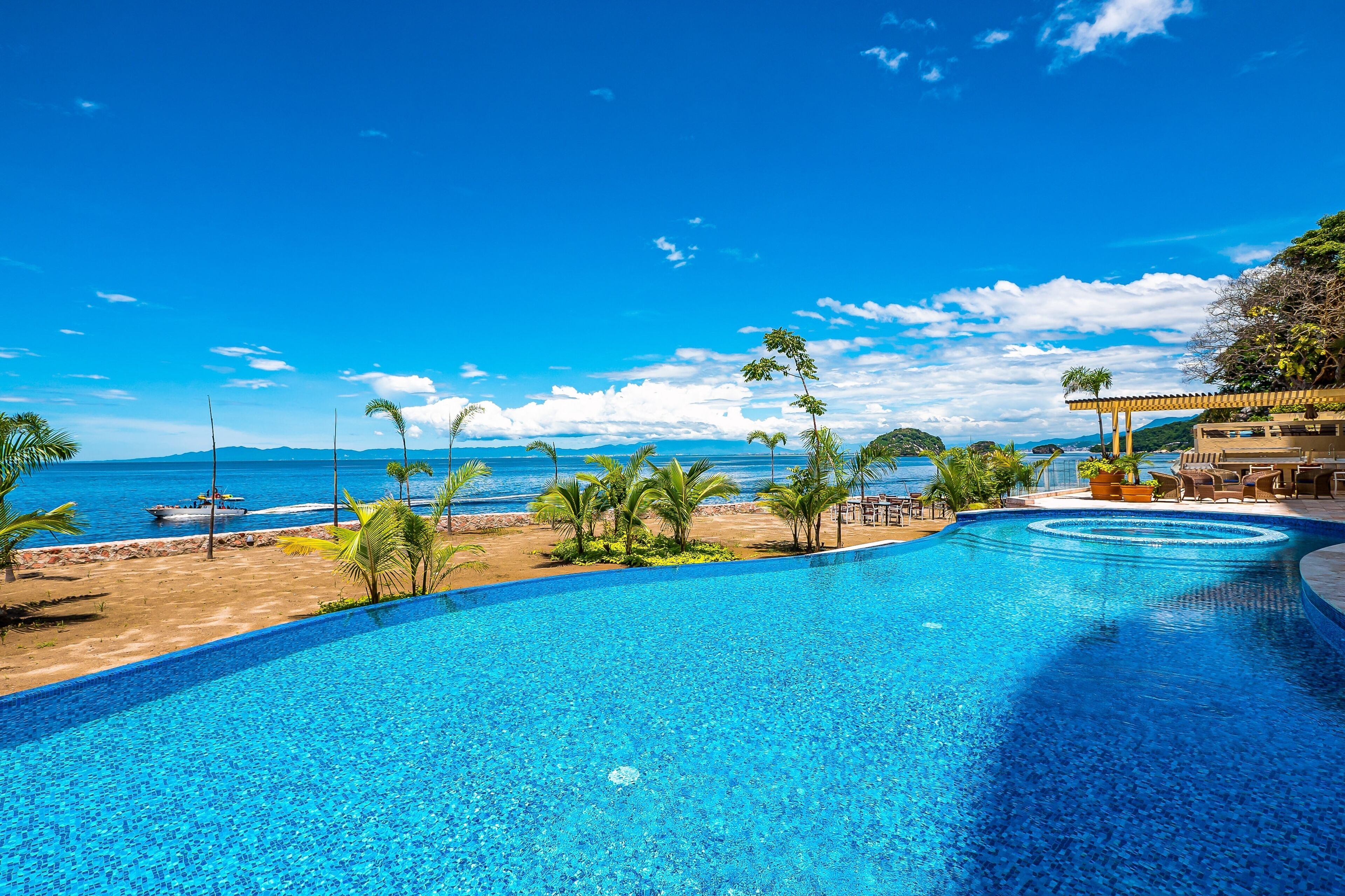 A clear blue pool with a view of the beach and ocean.