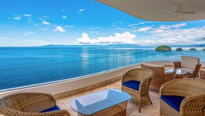 A balcony with wicker furniture, a glass table, and a view of the ocean. - Blue Horizon 601 | 1BR/2BA Puerto Vallarta | Ocean Views, Pool, Gym (Puerto Vallarta)