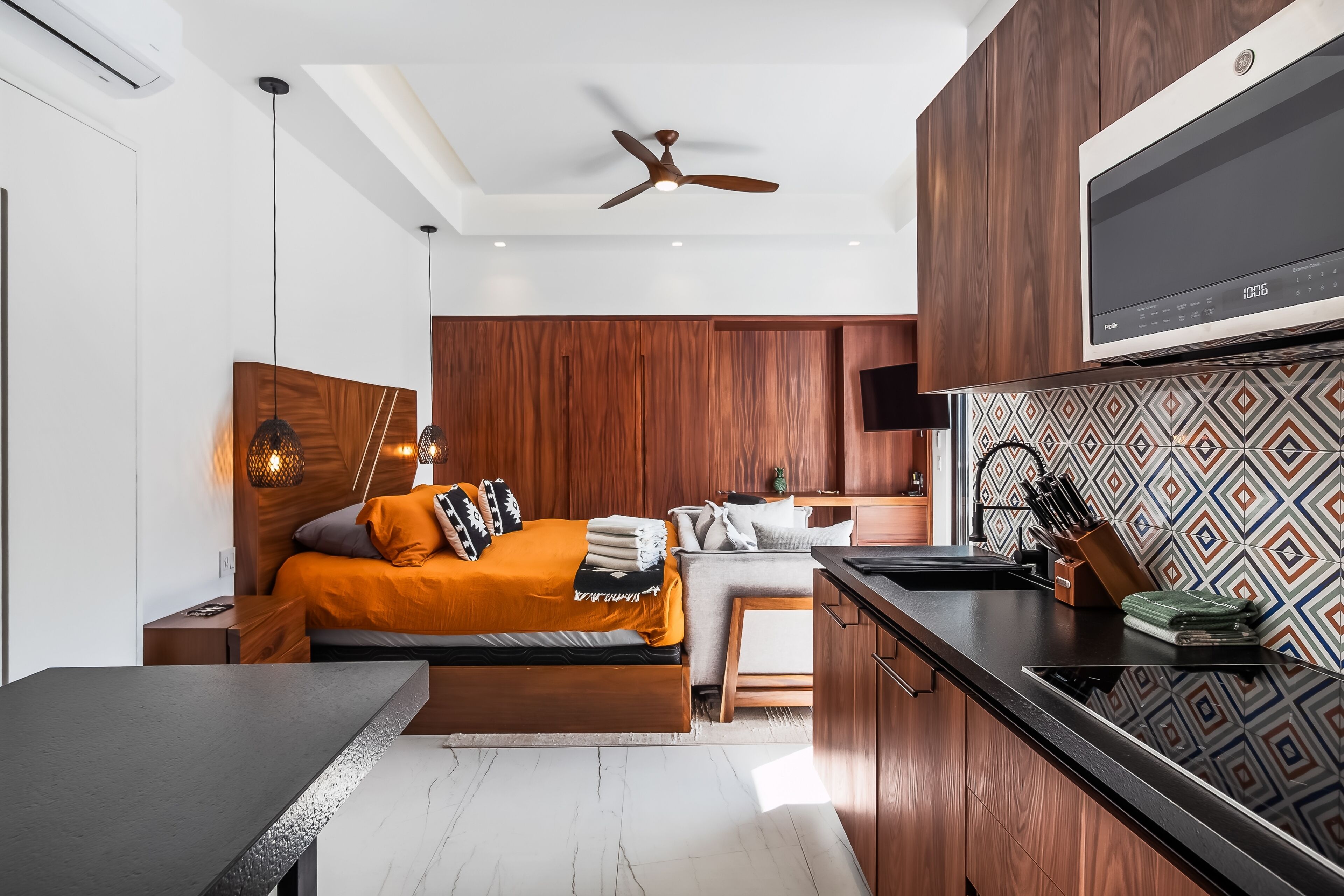A modern kitchen with a microwave, wooden cabinets, and a patterned backsplash.