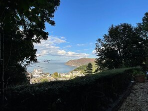 A coastal view with a clear sky, a body of water, and a distant mountain. - Rookery Cottage, Lynton (Lynton)