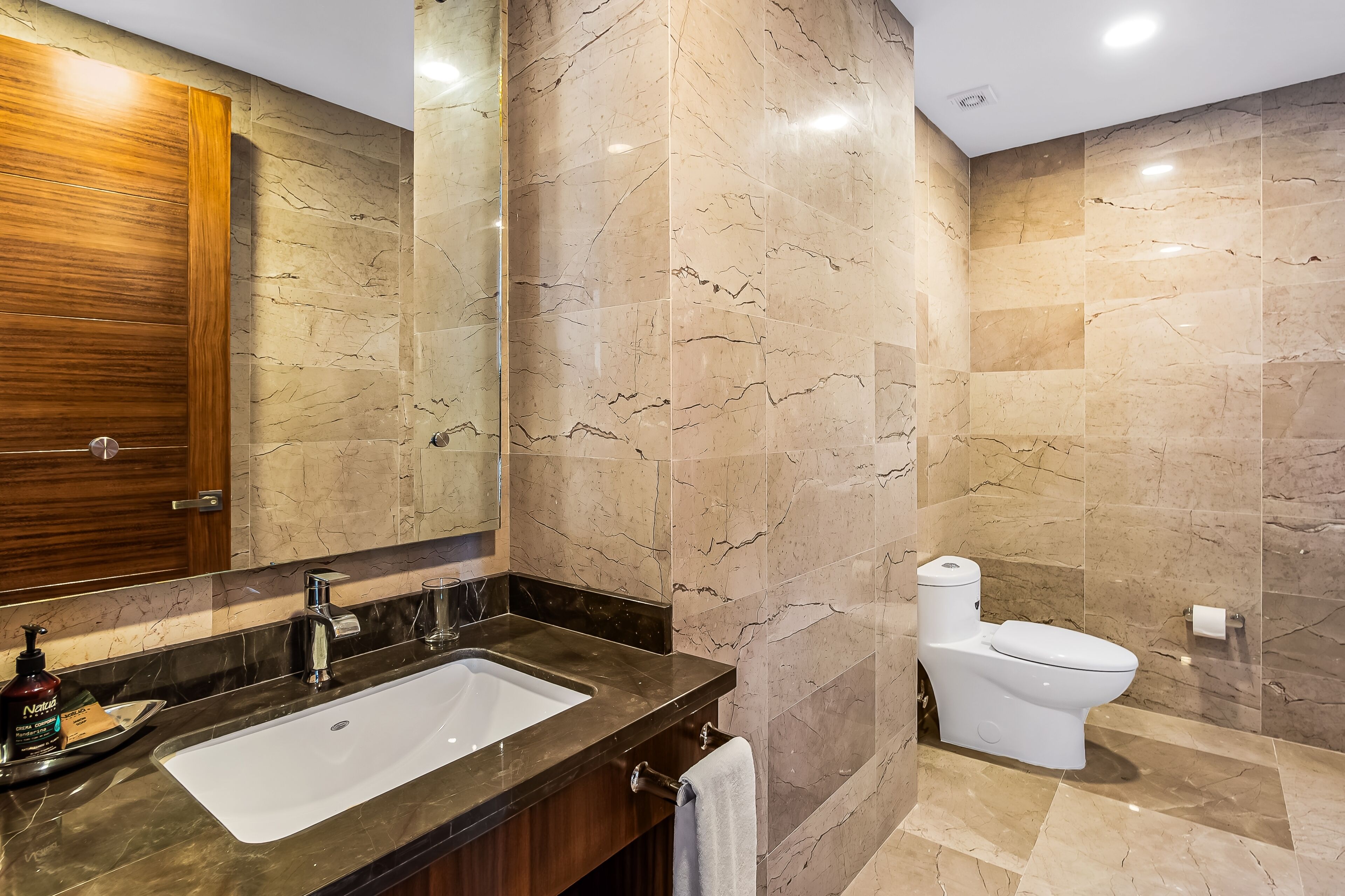 Une salle de bain moderne avec un lavabo en marbre, des toilettes et un meuble-lavabo en bois.